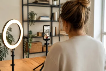 Personne filmant une vidéo TikTok dans un salon avec trépied et ring light allumée