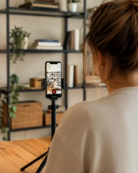 Personne filmant une vidéo TikTok dans un salon avec trépied et ring light allumée